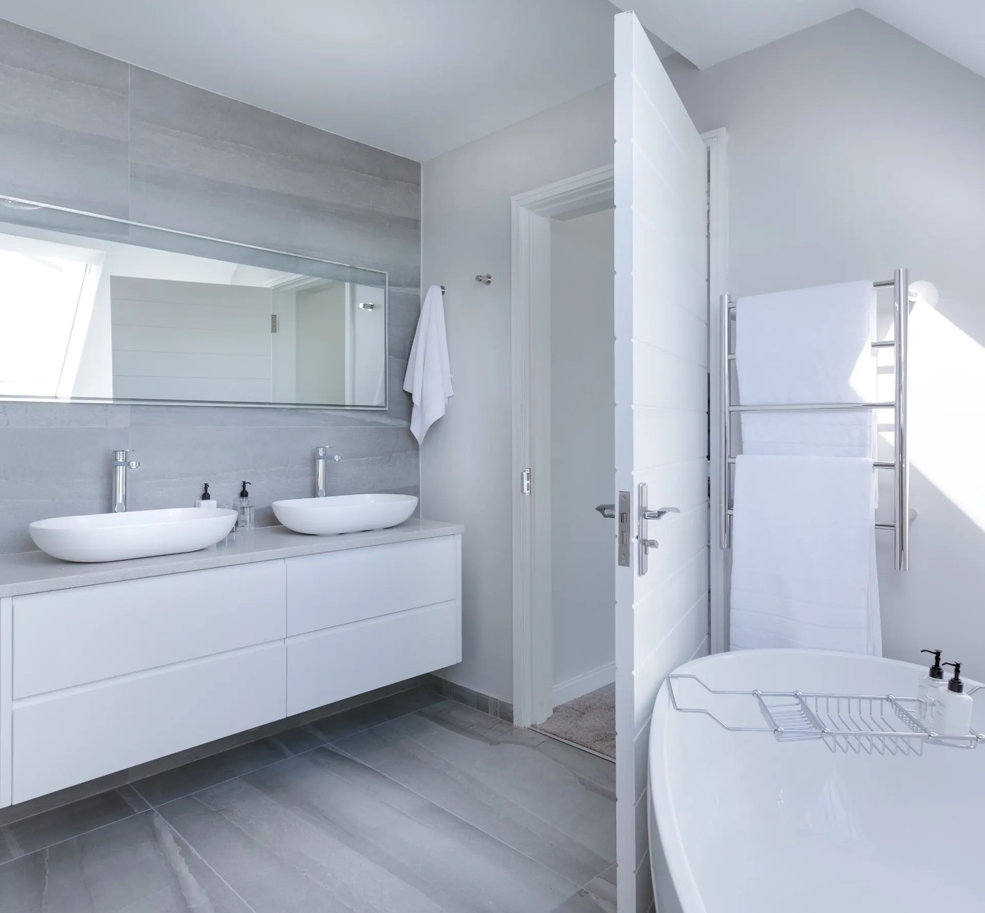 Modernes weißes Badezimmer mit Doppelwaschtisch, großem Spiegel und freistehender Badewanne
